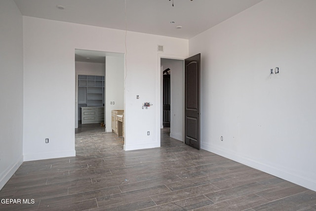 unfurnished bedroom featuring visible vents, a spacious closet, wood finished floors, and baseboards