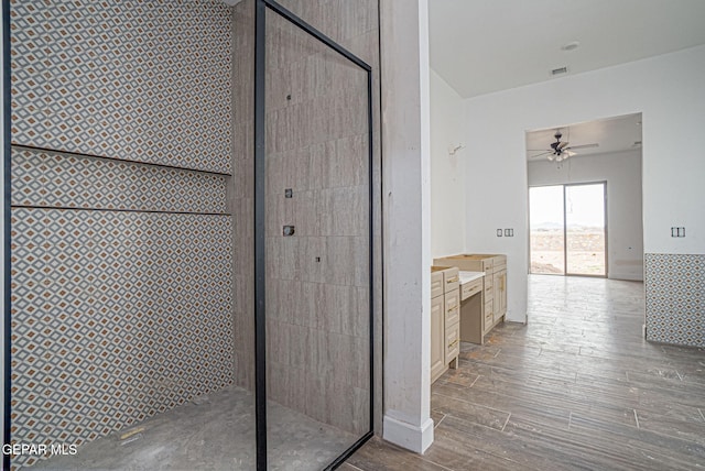 bathroom with visible vents, ceiling fan, tiled shower, wood finished floors, and vanity