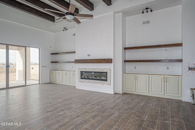 unfurnished living room featuring visible vents, dark wood-type flooring, ceiling fan, beamed ceiling, and a tile fireplace