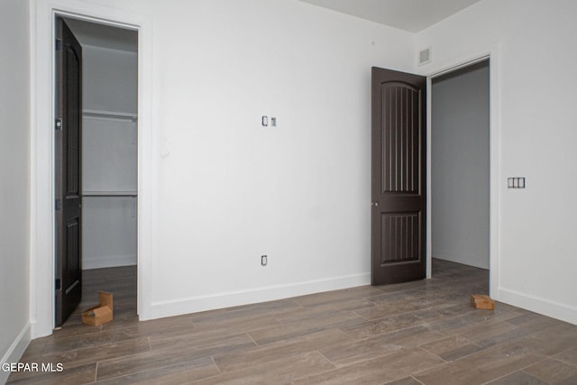 unfurnished bedroom with a closet, visible vents, baseboards, and wood finished floors