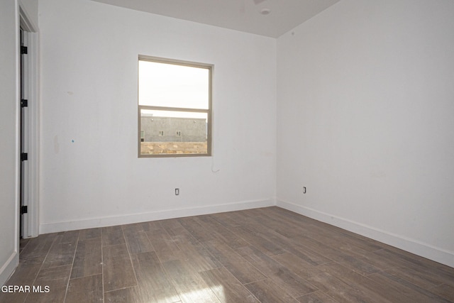 empty room with dark wood-type flooring and baseboards