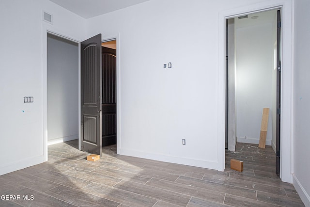 unfurnished bedroom with visible vents, baseboards, and wood finish floors