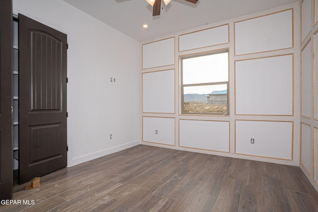 unfurnished bedroom with dark wood-type flooring, a decorative wall, recessed lighting, and baseboards