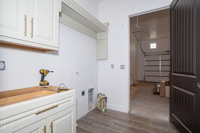 clothes washing area featuring baseboards, wood finish floors, a garage, cabinet space, and electric dryer hookup