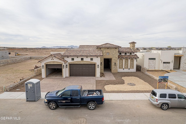 view of front of property featuring stucco siding, driveway, an attached garage, and a tile roof