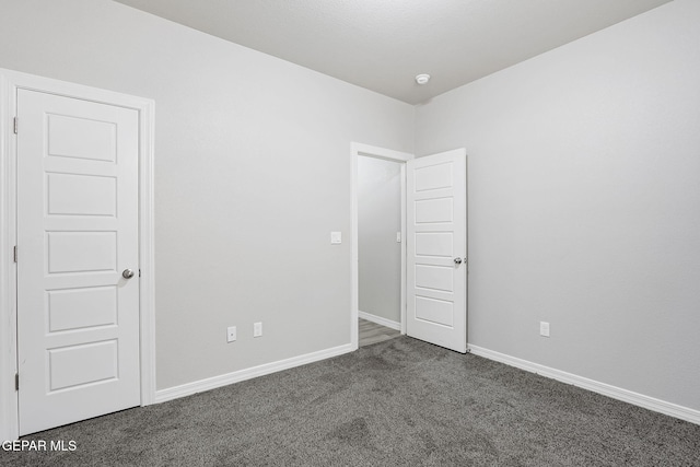 unfurnished room with carpet flooring and baseboards