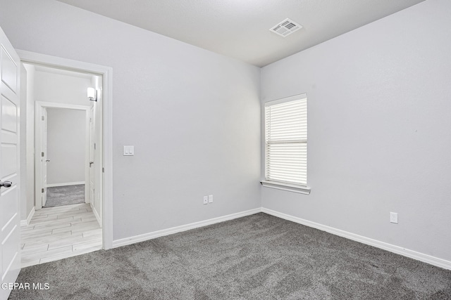 unfurnished room with baseboards, visible vents, and light carpet