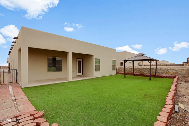 rear view of property with a gazebo, stucco siding, a patio, and fence