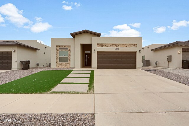 view of front facade featuring stucco siding, central air condition unit, a garage, and driveway