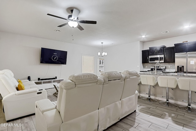 living area featuring wood finish floors, visible vents, recessed lighting, and ceiling fan with notable chandelier