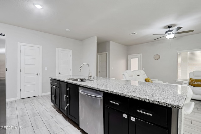 kitchen featuring a ceiling fan, a sink, stainless steel dishwasher, open floor plan, and dark cabinetry