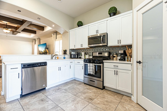 kitchen with a sink, coffered ceiling, appliances with stainless steel finishes, light countertops, and decorative backsplash