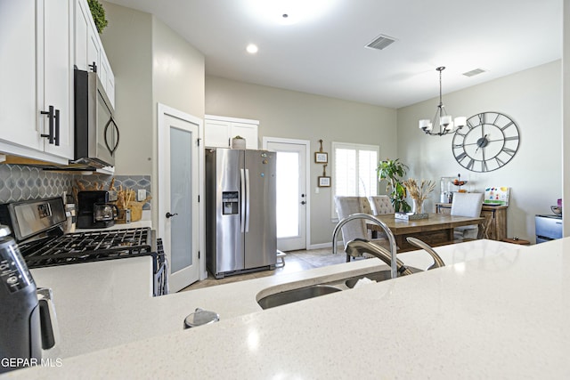 kitchen featuring tasteful backsplash, visible vents, appliances with stainless steel finishes, and a sink