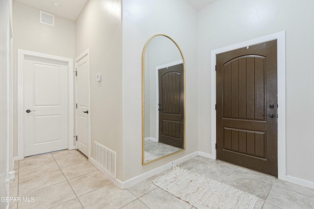 entryway with light tile patterned floors, baseboards, and visible vents