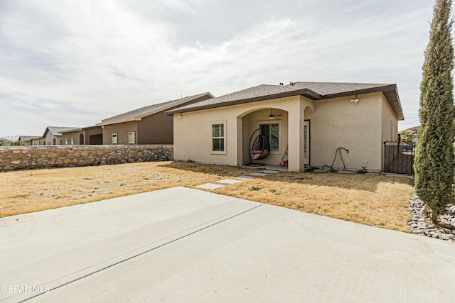 view of front of home featuring stucco siding, a patio, fence, roof with shingles, and ceiling fan