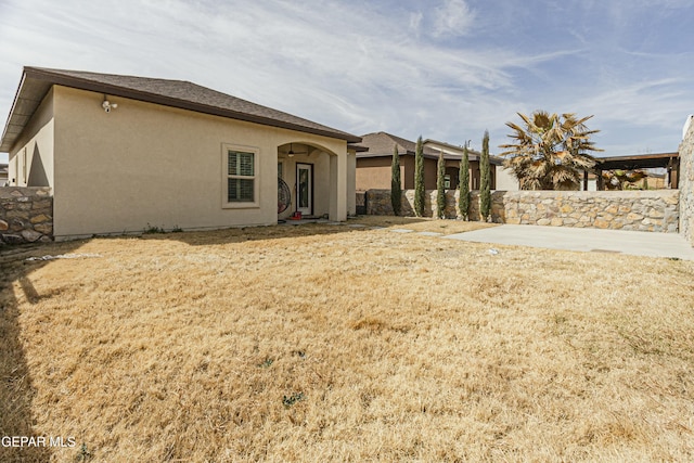 rear view of property featuring stucco siding and a lawn