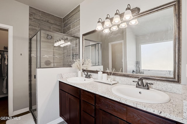 bathroom with double vanity, a shower stall, a walk in closet, and a sink