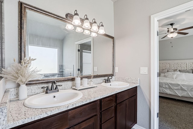 ensuite bathroom featuring a sink, connected bathroom, ceiling fan, and double vanity