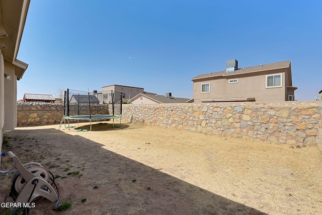 view of yard with a trampoline and a fenced backyard