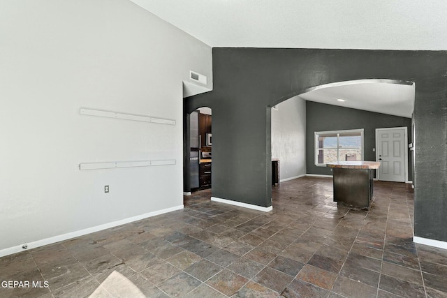 empty room featuring arched walkways, visible vents, baseboards, and lofted ceiling