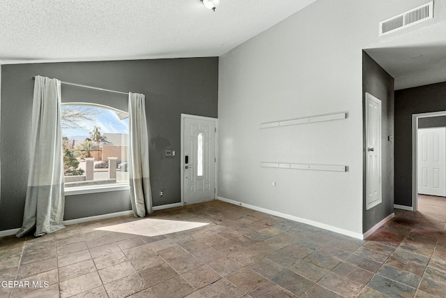 foyer featuring visible vents, baseboards, a textured ceiling, and stone finish floor