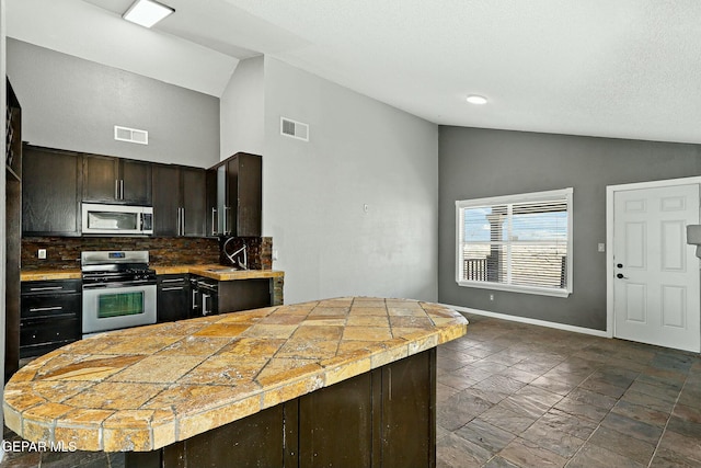 kitchen with a sink, stainless steel appliances, lofted ceiling, and visible vents