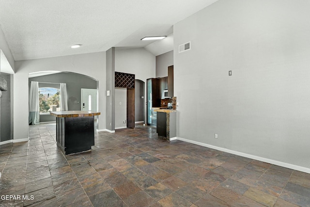 kitchen with visible vents, arched walkways, baseboards, and light countertops