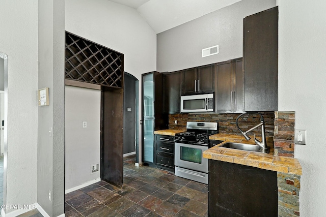 kitchen featuring a sink, stone tile floors, visible vents, and stainless steel appliances