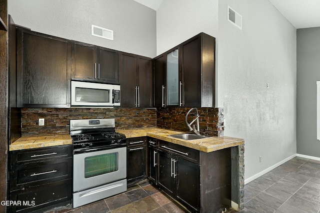 kitchen with visible vents, backsplash, baseboards, appliances with stainless steel finishes, and a sink