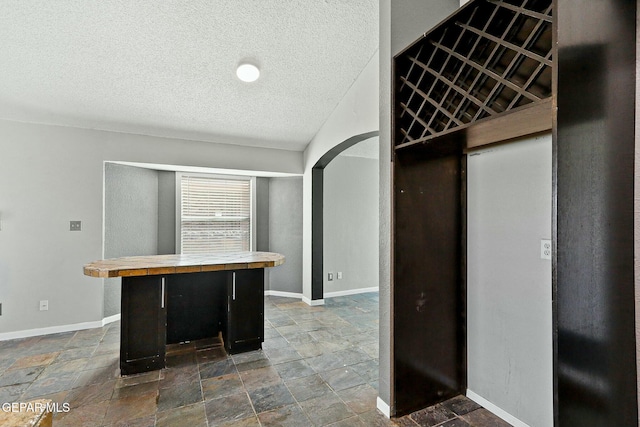 kitchen with a textured ceiling, baseboards, and stone finish flooring