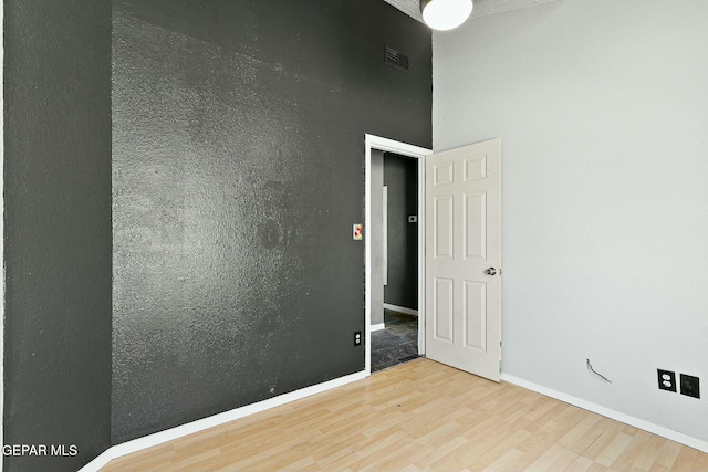 empty room with visible vents, baseboards, and wood finished floors