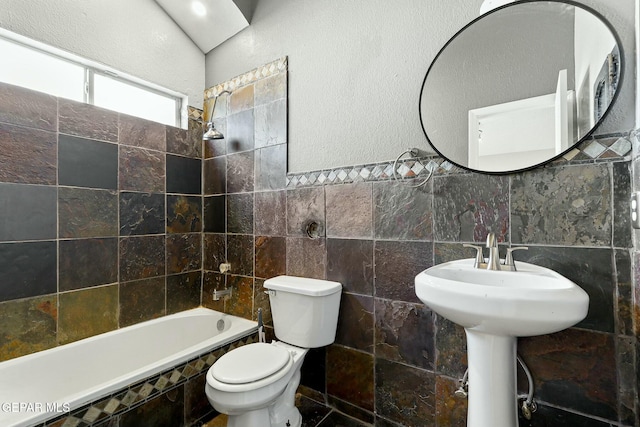 bathroom with toilet, tile walls, tiled shower / bath combo, and a sink