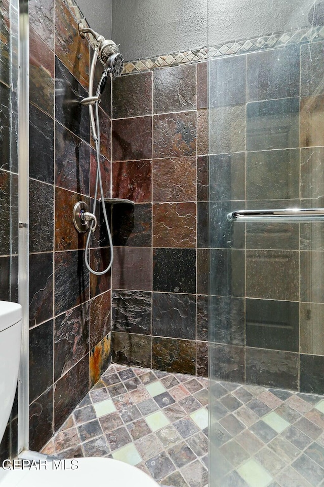 full bath with toilet and a tile shower