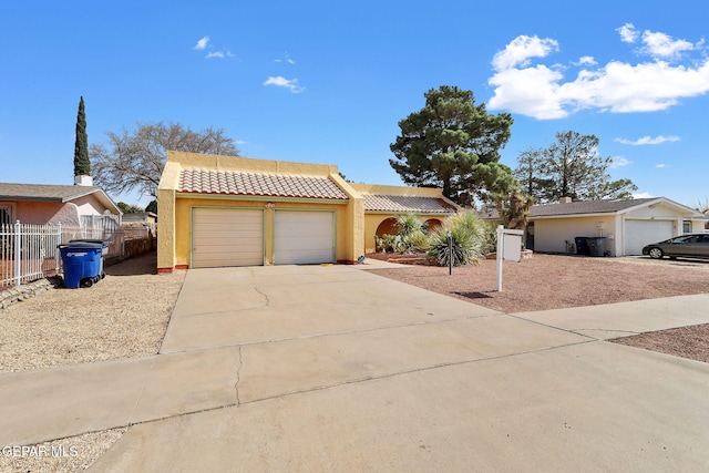 view of front of house with fence, a tile roof, stucco siding, a garage, and driveway