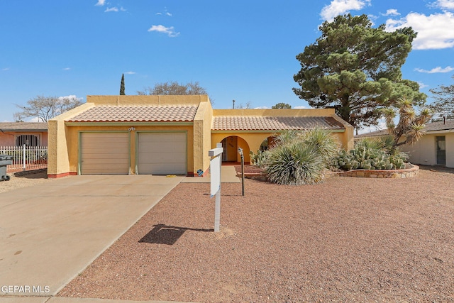 view of front of house with stucco siding, a tile roof, fence, concrete driveway, and an attached garage