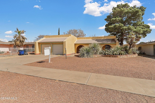 view of front of home featuring stucco siding, driveway, a tile roof, fence, and a garage