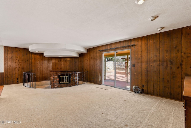 carpeted living area with a textured ceiling, a brick fireplace, and wood walls