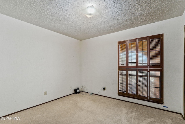 carpeted spare room featuring a textured ceiling and baseboards