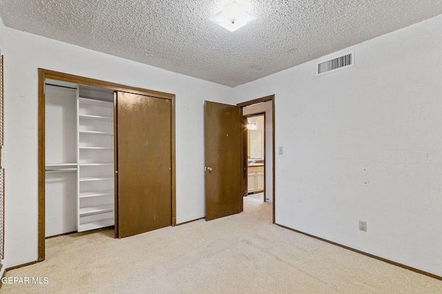 unfurnished bedroom with visible vents, a textured ceiling, a closet, carpet, and baseboards