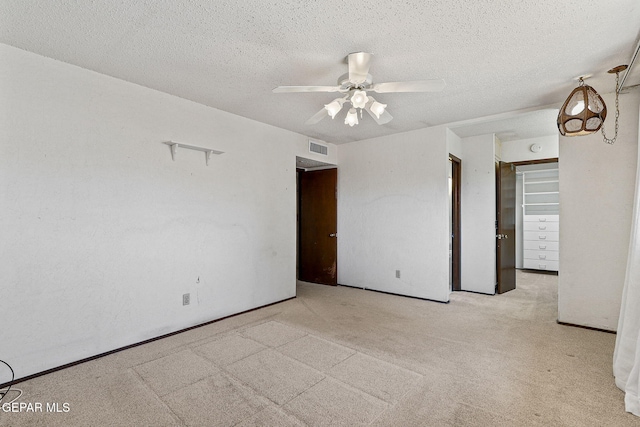 carpeted empty room featuring a ceiling fan, visible vents, and a textured ceiling