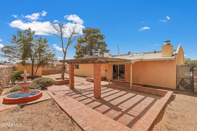 rear view of property featuring a gate, stucco siding, a patio, and fence