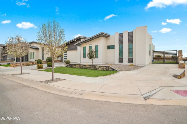 view of front of home featuring stucco siding, concrete driveway, and a front lawn