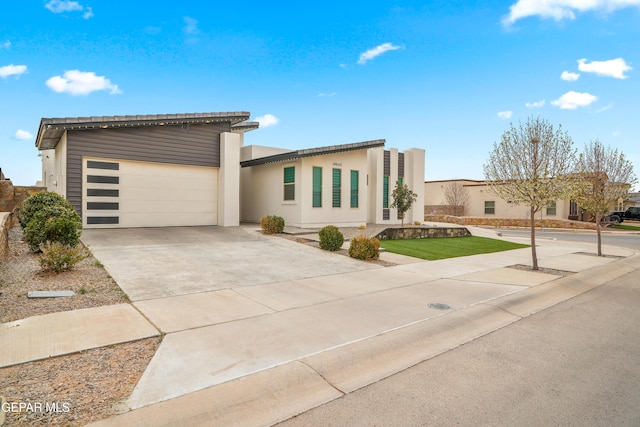 contemporary house with an attached garage, driveway, and stucco siding