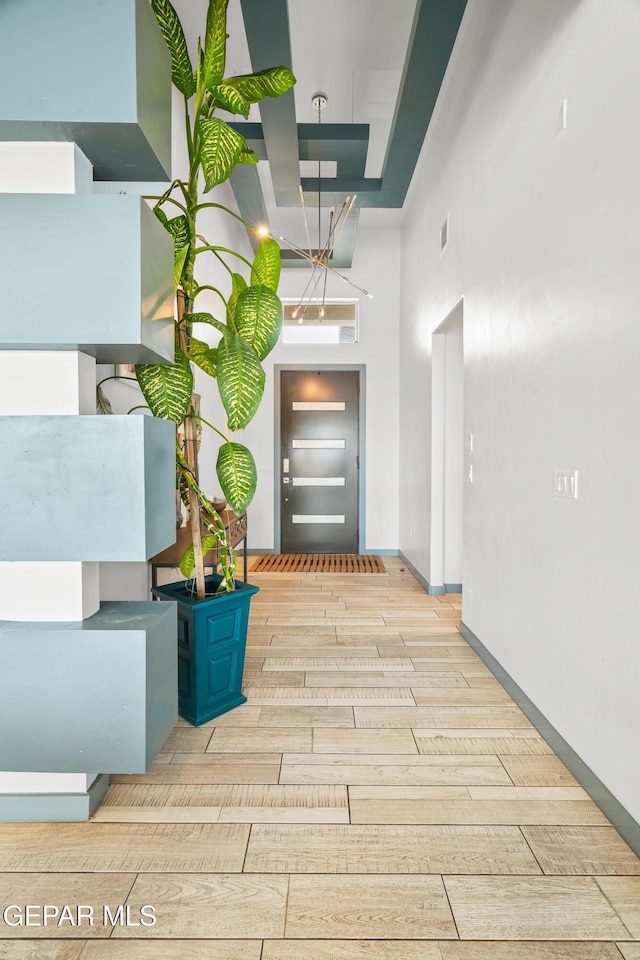 corridor with visible vents, baseboards, a towering ceiling, and wood tiled floor