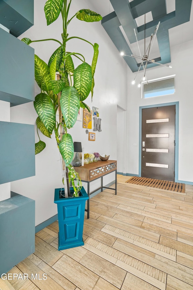 entrance foyer featuring wood finish floors, baseboards, and a high ceiling