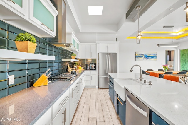 kitchen featuring decorative backsplash, appliances with stainless steel finishes, white cabinets, a raised ceiling, and a sink