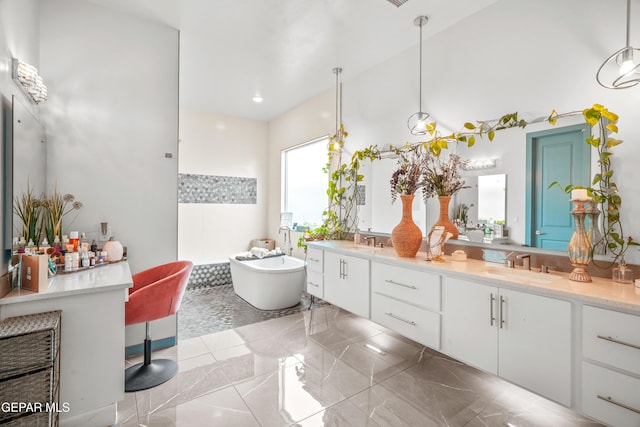 bathroom featuring double vanity, a freestanding bath, and a sink