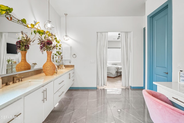 ensuite bathroom with a sink, ensuite bathroom, marble finish floor, and double vanity