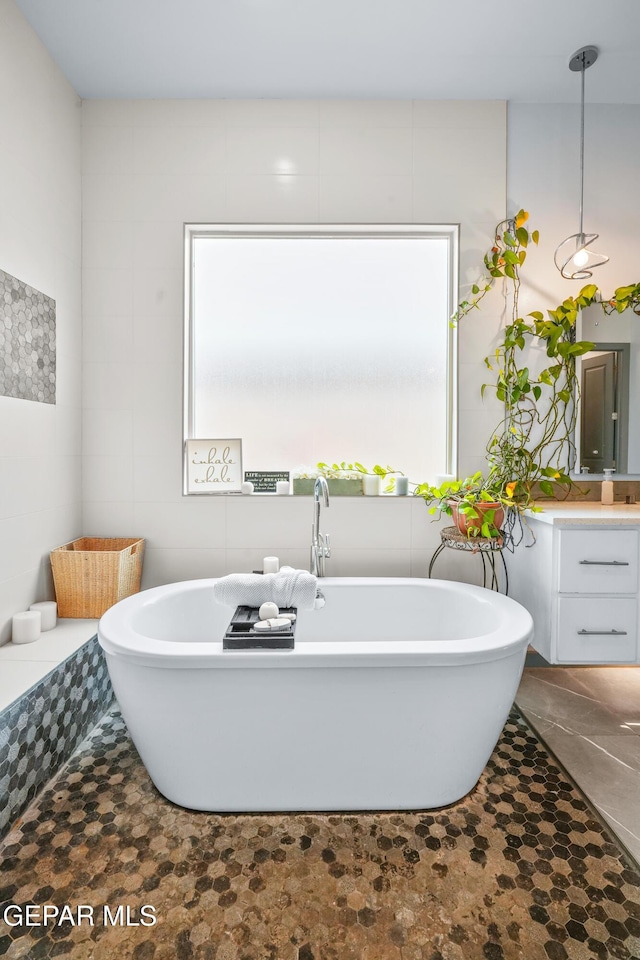 bathroom featuring vanity, tile walls, and a freestanding tub