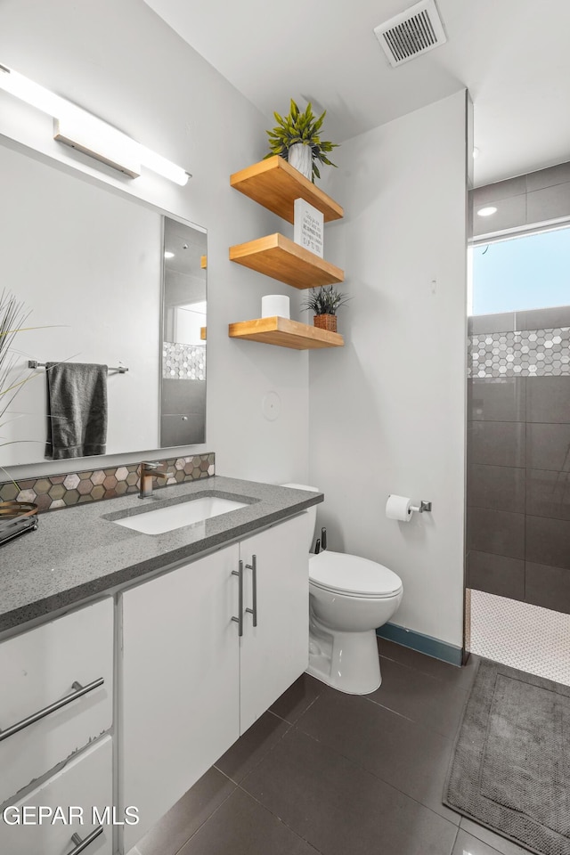 bathroom with visible vents, toilet, tile patterned flooring, tiled shower, and vanity